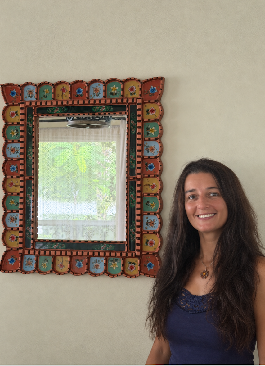 Ulviya Bemman standing beside one of her colorful hand-painted floral mirrors